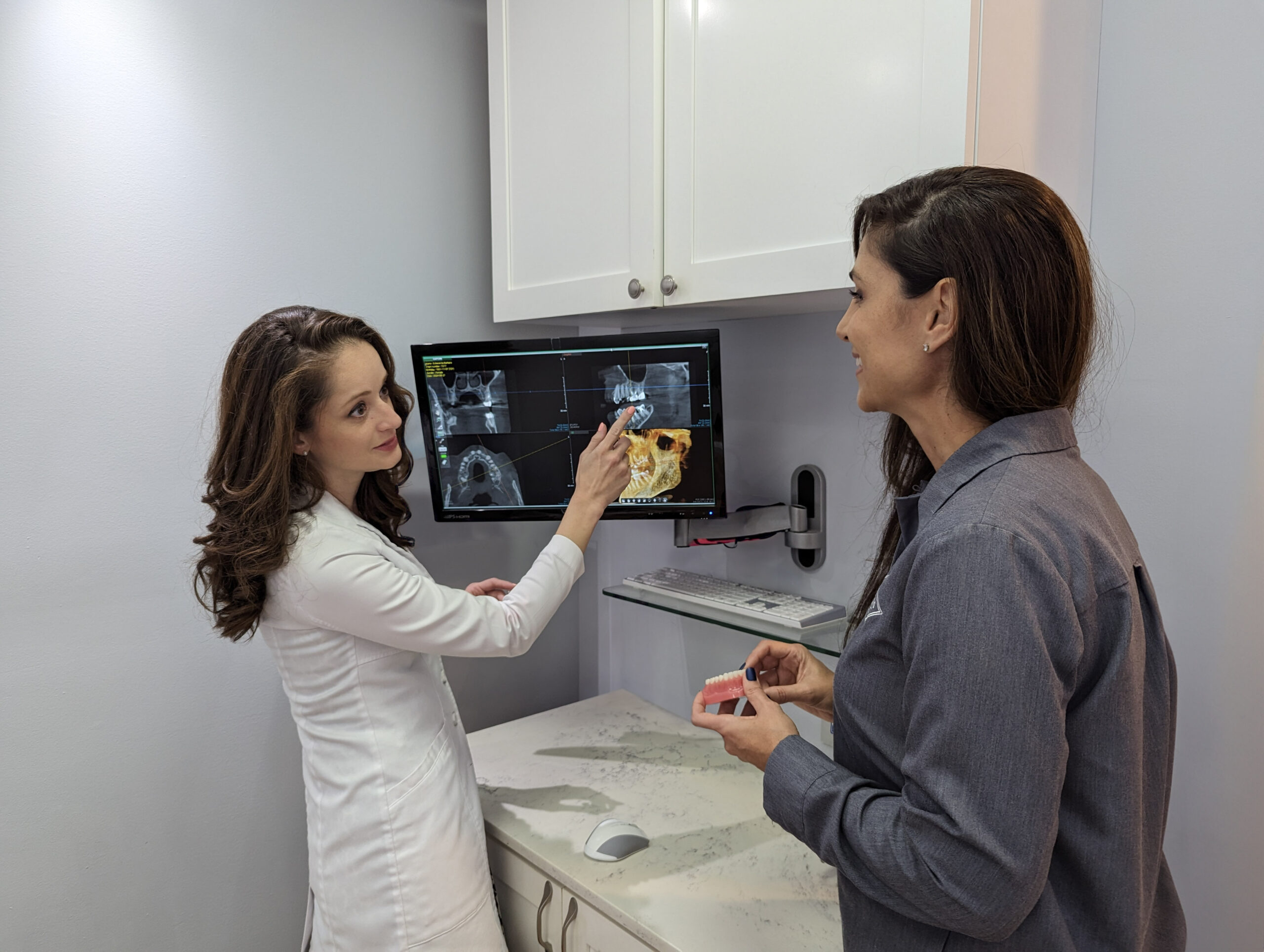 Dr. Yenile Y. Pinto reviewing a 3D CBCT scan with a team member at Deering Dental